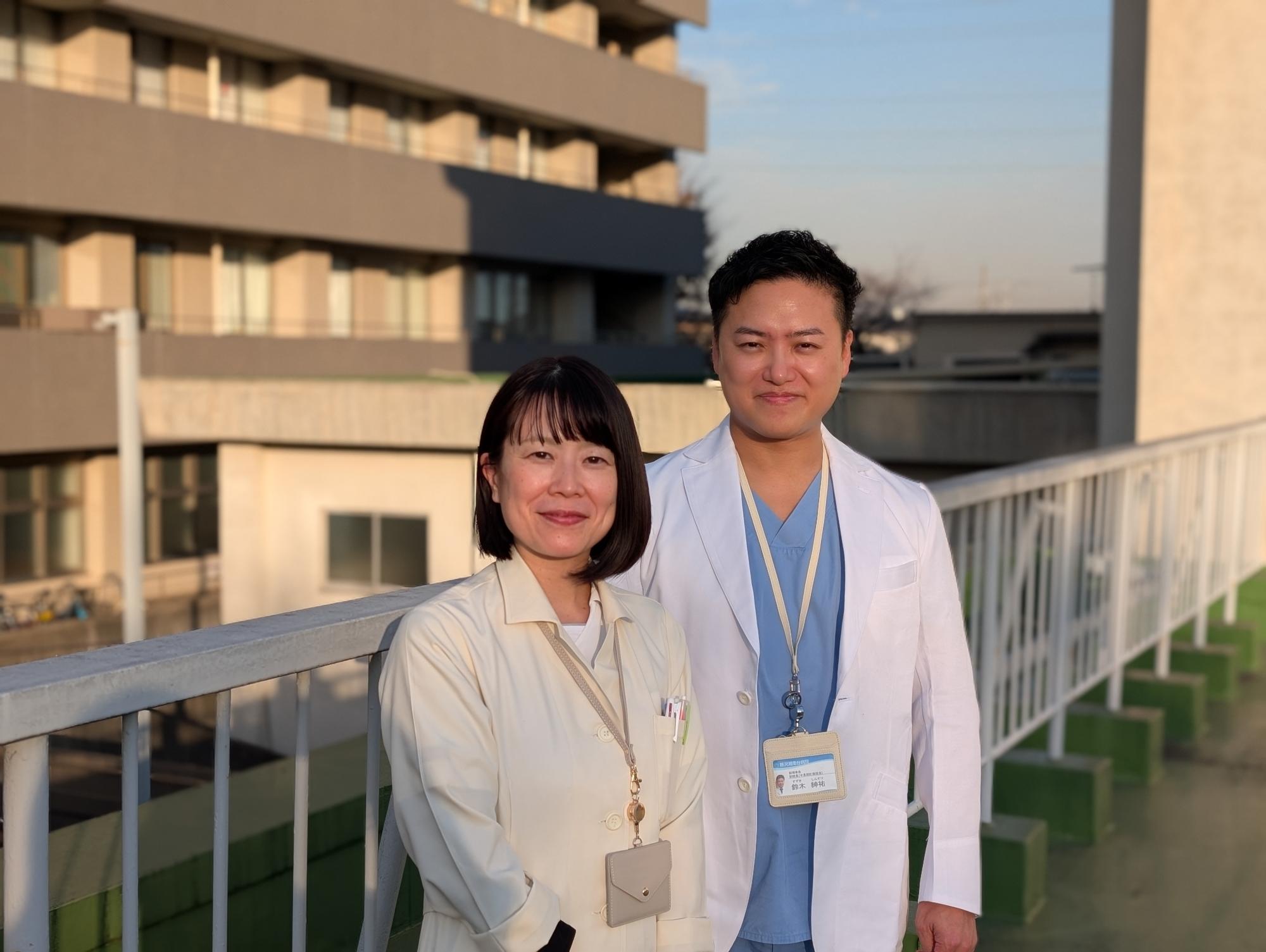 1号館を背景に2号館テラスにて　右・鈴木紳祐副院長　左・小原由里さん